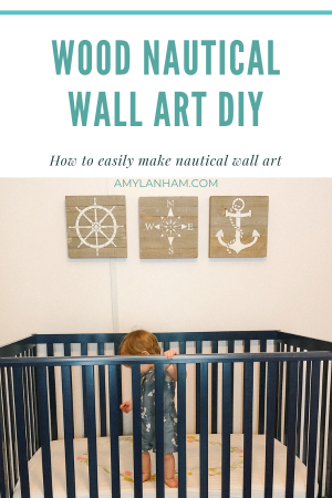 child in crib with three wooden nautical painted wall arts above it