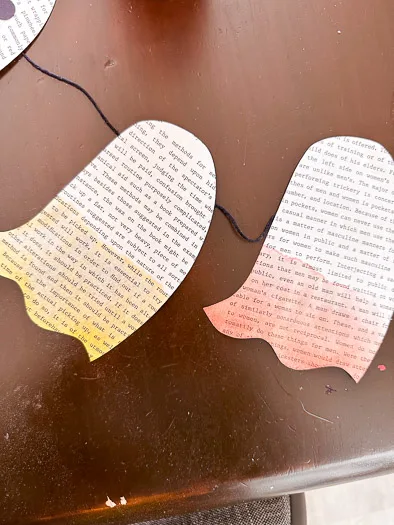 2 book page ghosts with their bottom halves painted, one yellow, one red.