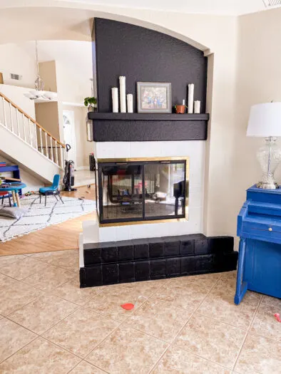 fireplace with the surround tile painted white and the bottom tile painted black, the top wall is also painted black.