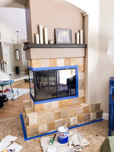 fireplace with a beige tile surround, had blue tape around the fireplace and tile on the floor