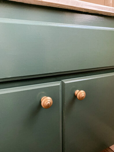 close up of a green cabinet with gold knobs