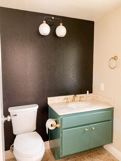bathroom with green cabinet and black wall behind sink 